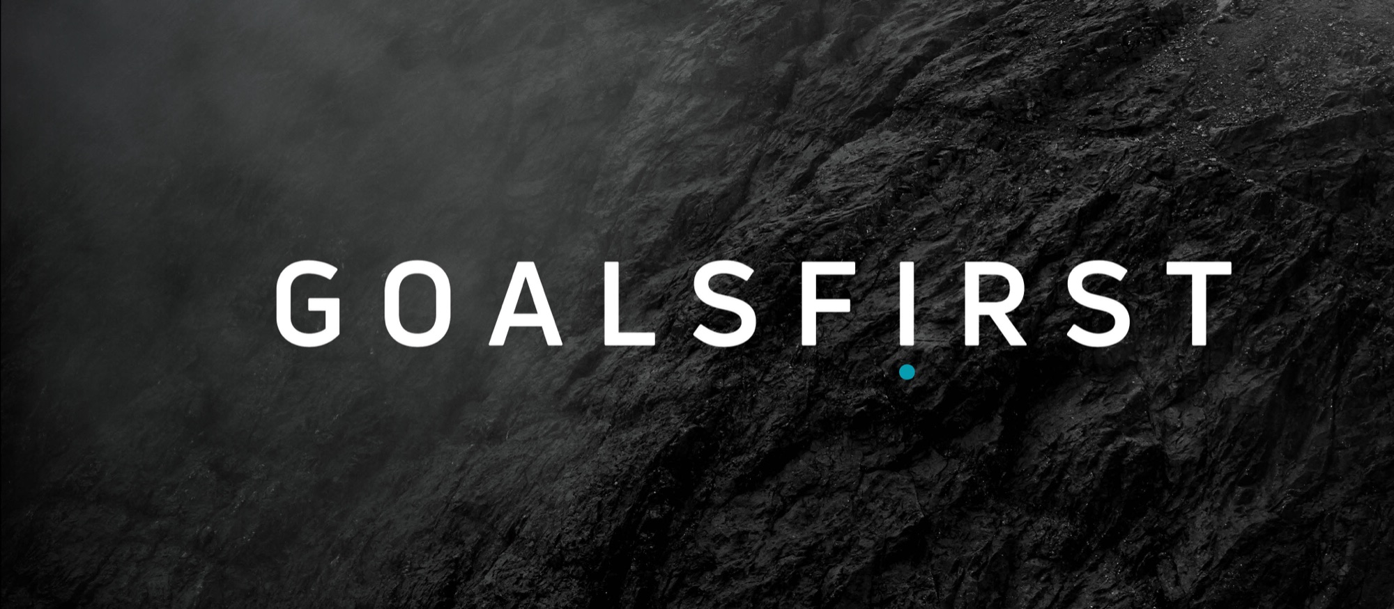 The GOALSFIRST wordmark in widely letterspaced white capitals across a dark volcanic rock face, with a cyan dot set beneath the I in place of its tittle